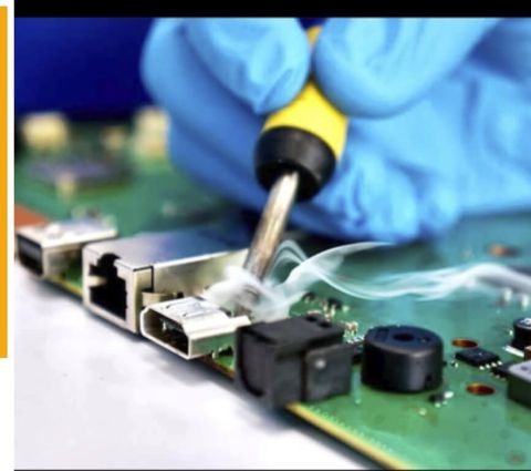 A replacement HDMI port being soldered onto a games console mainboard