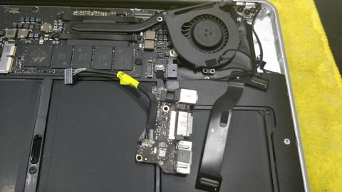 MacBook opened for repair, showing the logic board, fan and IO board